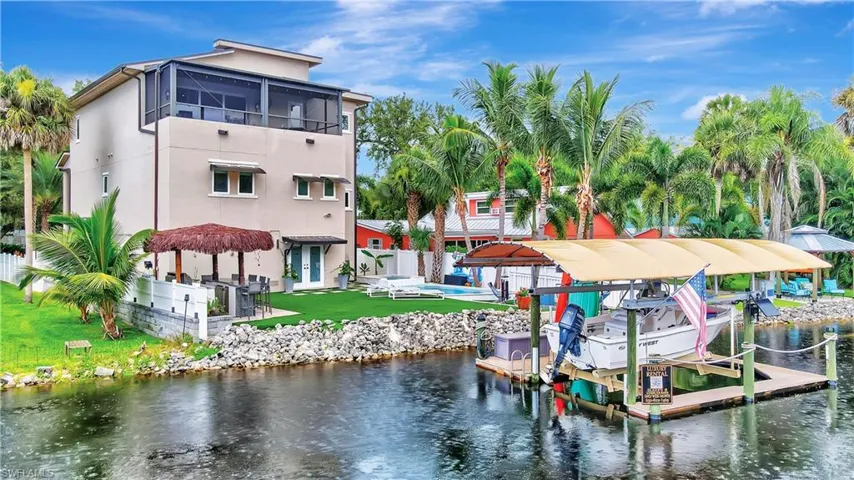 Backyard view showcasing tiki bar and covered boat lift (up to 7,000 lbs)