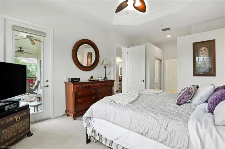 Bedroom featuring access to exterior, carpet flooring, a raised ceiling, ornamental molding, and a ceiling fan