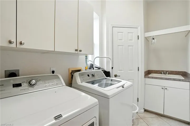 Washroom featuring cabinet space, light tile patterned flooring, and independent washer and dryer