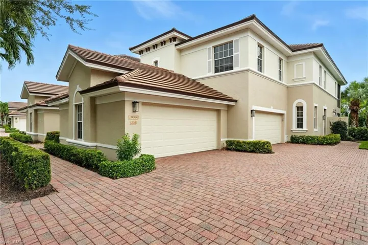 View of front facade featuring a tile roof, stucco siding, and decorative driveway