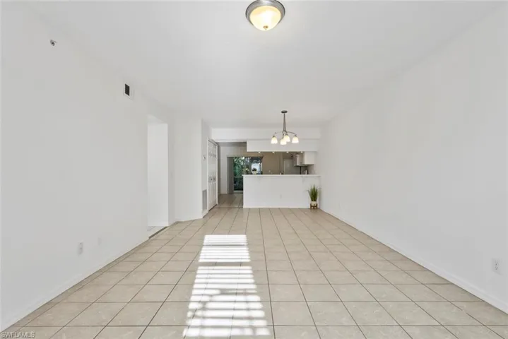 Unfurnished living room featuring light tile patterned flooring and an inviting chandelier