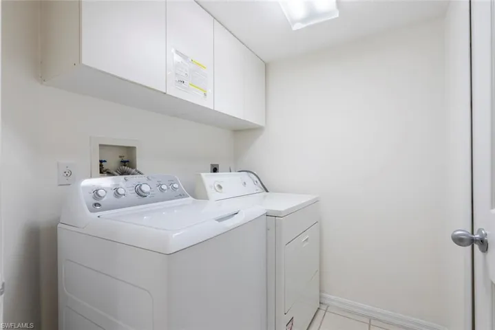 Laundry room with cabinets, light tile patterned floors, and separate washer and dryer