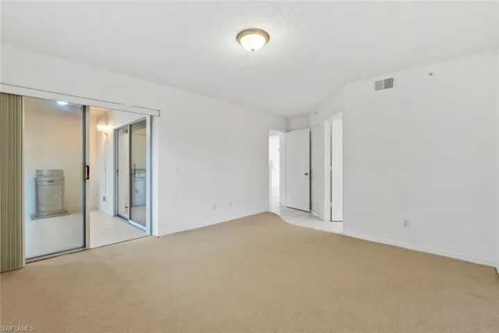Guest bedroom featuring light carpet and a textured ceiling