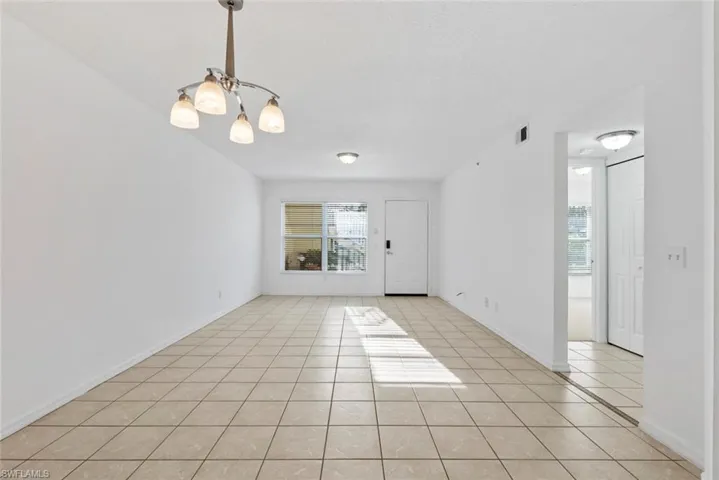 Spare room with light tile patterned floors and a notable chandelier
