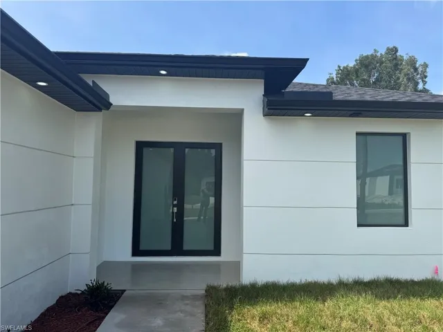Entrance to property with roof with shingles, stucco siding, and french doors