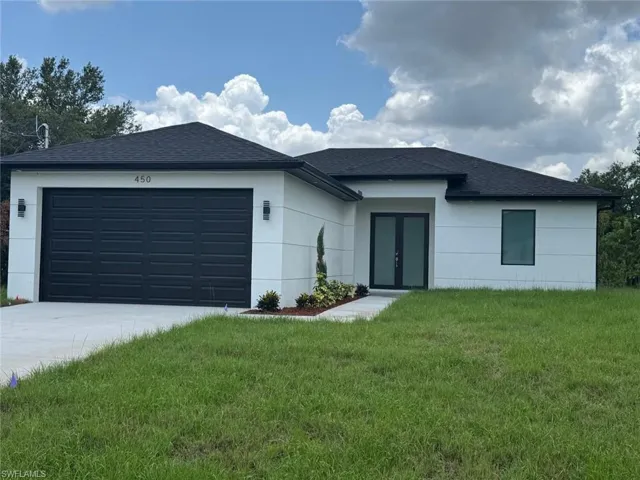 View of front of house with french doors, concrete driveway, an attached garage, a shingled roof, and a front lawn