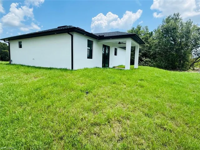 Back of property with a yard, stucco siding, and a ceiling fan