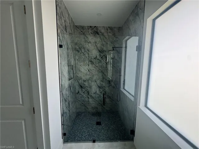 Full bathroom with a marble finish shower