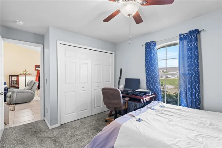 Carpeted bedroom with ceiling fan and a closet