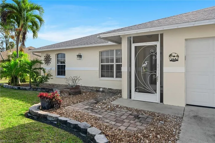 View of exterior entry with a garage and a lawn