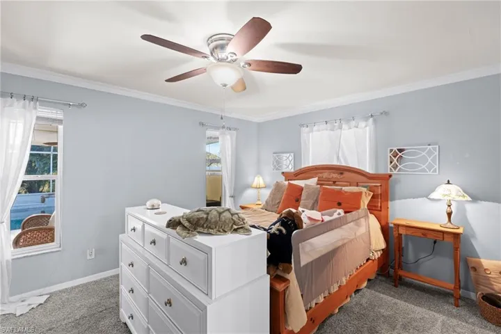 Carpeted bedroom featuring crown molding and ceiling fan
