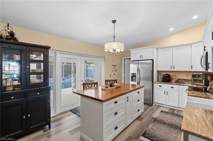 Kitchen featuring pendant lighting, appliances with stainless steel finishes, a center island, and white cabinets