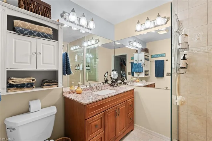 Bathroom featuring vanity, tile patterned flooring, a shower with door, and toilet