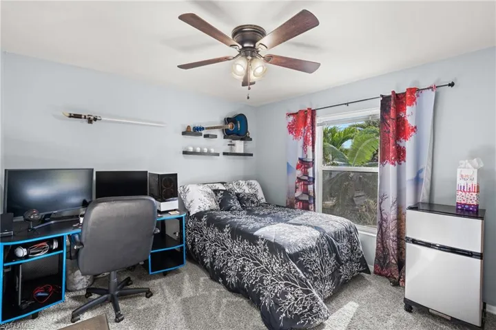 Carpeted bedroom featuring stainless steel fridge and ceiling fan