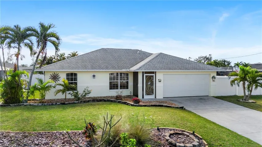 Single story home with a garage and a front lawn
