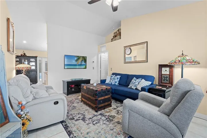 Tiled living room with vaulted ceiling and ceiling fan