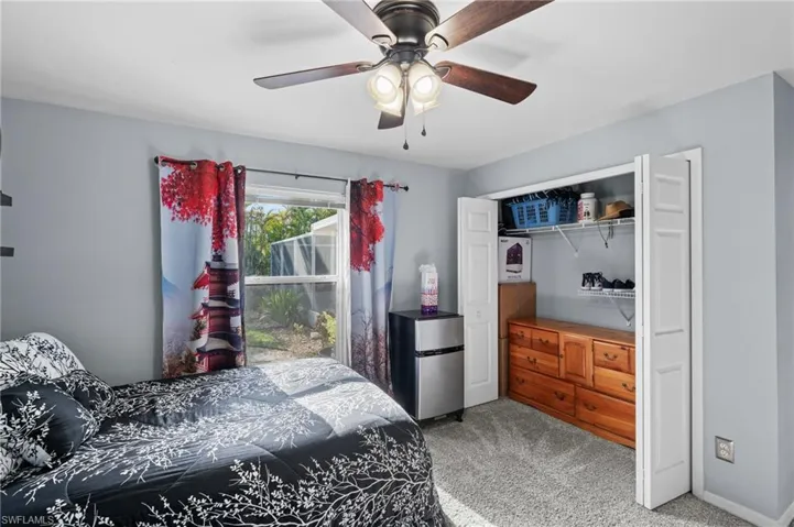Carpeted bedroom with ceiling fan, stainless steel refrigerator, and a closet