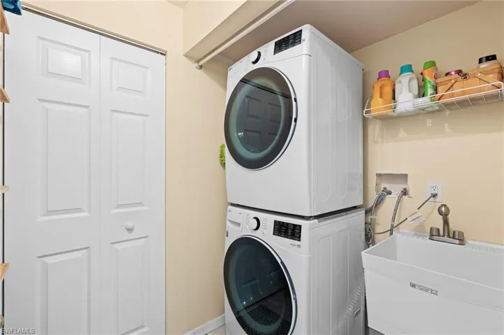 Washroom with stacked washer / drying machine and sink
