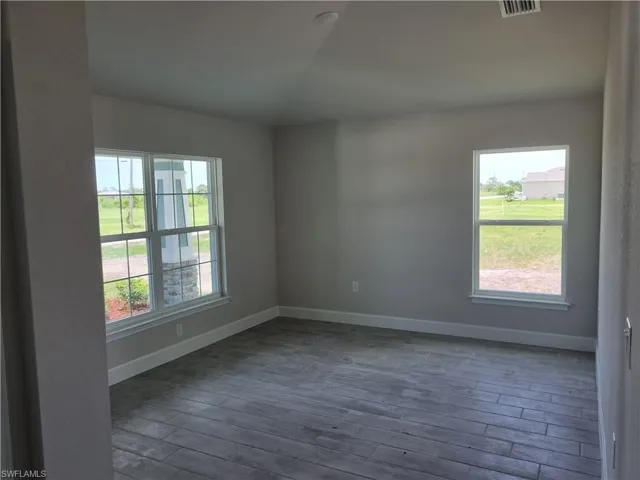 Empty room with dark wood-style flooring and lofted ceiling