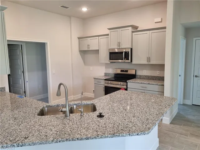 Kitchen with stainless steel appliances, light stone countertops, light wood-style flooring, a peninsula, and recessed lighting