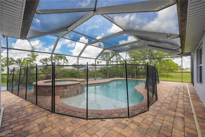 View of swimming pool featuring a patio, an in ground hot tub, and glass enclosure