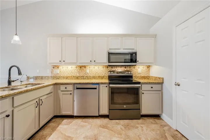 Kitchen featuring appliances with stainless steel finishes, lofted ceiling, light tile patterned floors, and sink