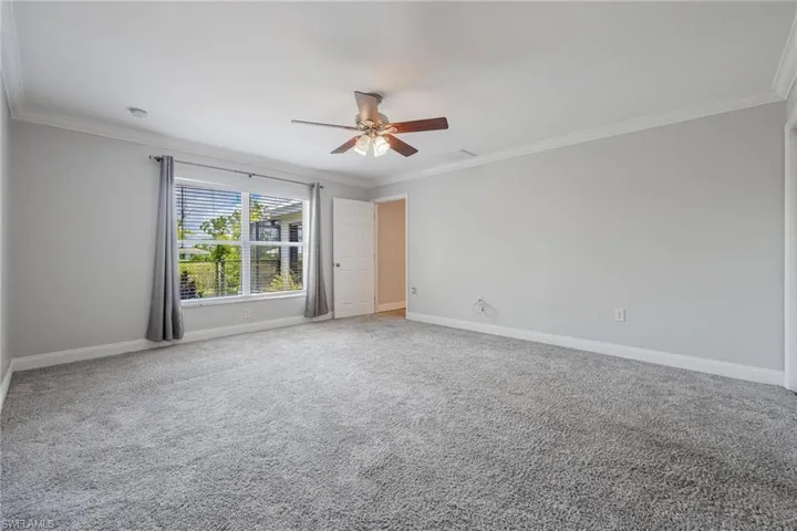Carpeted main bedroom room with crown molding and ceiling fan
