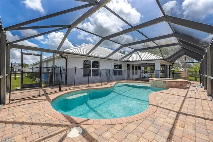 View of pool featuring a patio area, an in ground hot tub, and glass enclosure