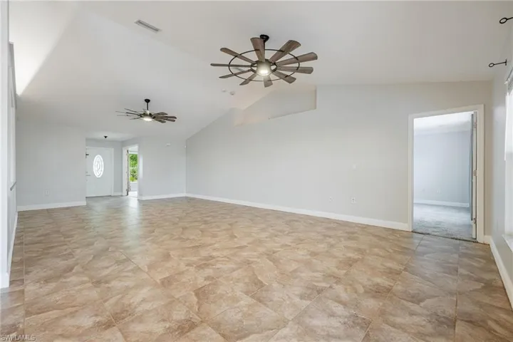 Unfurnished room with light tile patterned floors, vaulted ceiling, and ceiling fan