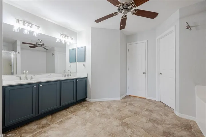 Bathroom with dual vanity, tile patterned flooring, and ceiling fan