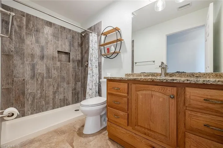 Bathroom with tile patterned flooring, walk in shower, toilet, and vanity