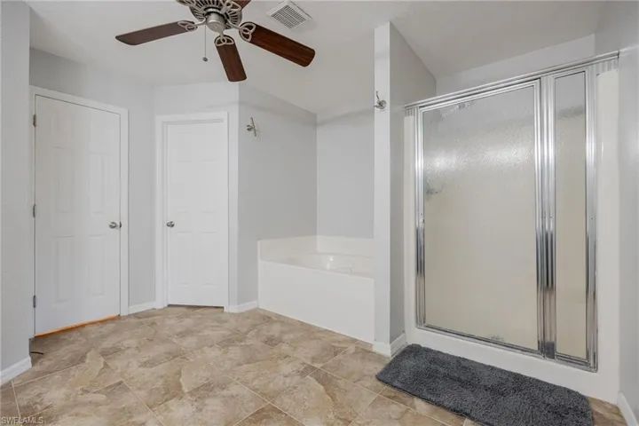 Bathroom with tile patterned floors, plus walk in shower, and ceiling fan