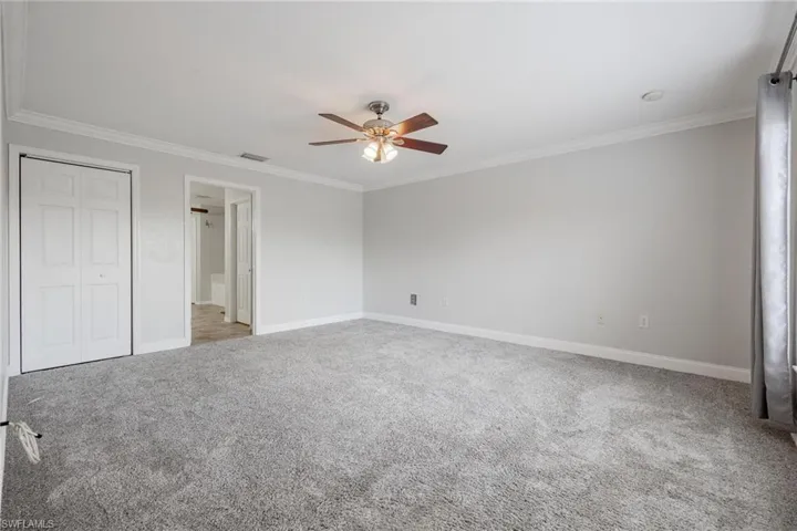 Unfurnished bedroom with carpet floors, crown molding, and ceiling fan