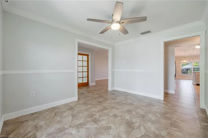 Tiled dining room featuring ceiling fan and crown molding