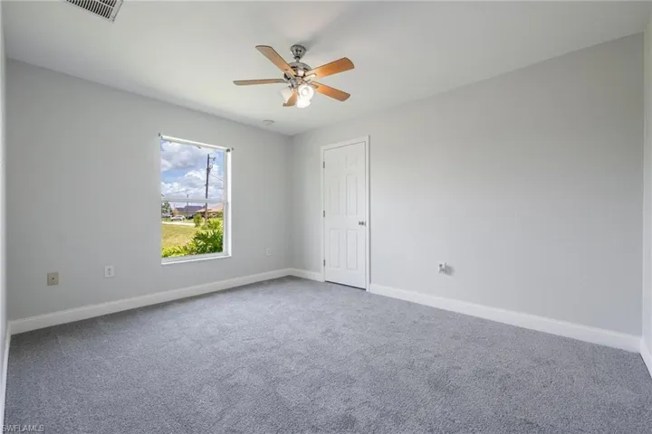 Carpeted empty room featuring ceiling fan