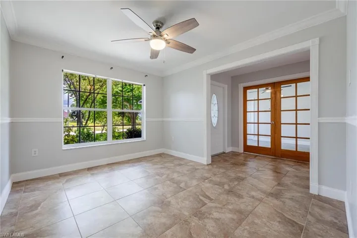 Tiled spare room with french doors, ceiling fan, and ornamental molding