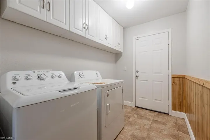 Laundry area featuring independent washer and dryer, cabinets, and light tile patterned floors