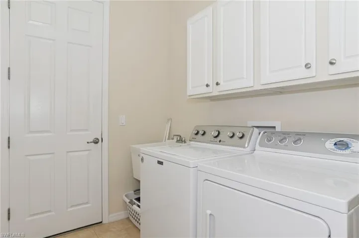 Laundry area with cabinet space, washer and clothes dryer, and light tile patterned floors
