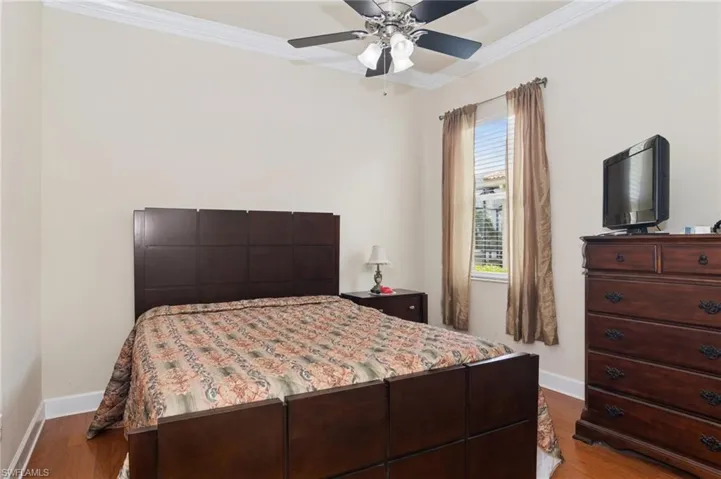 Bedroom with ornamental molding, wood finished floors, and a ceiling fan