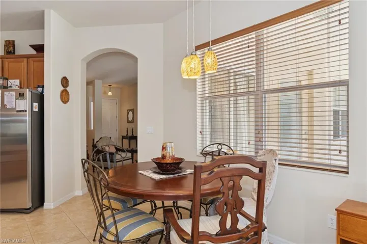 Dining room with arched walkways, light tile patterned floors, plenty of natural light, and a chandelier