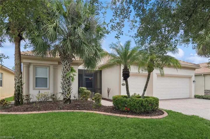 View of front of house with decorative driveway, stucco siding, a garage, a front lawn, and a tile roof