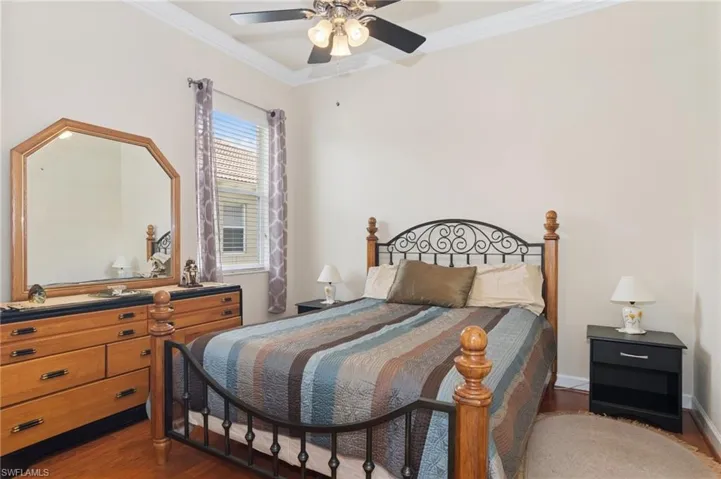 Bedroom with crown molding, dark wood-style floors, and a ceiling fan
