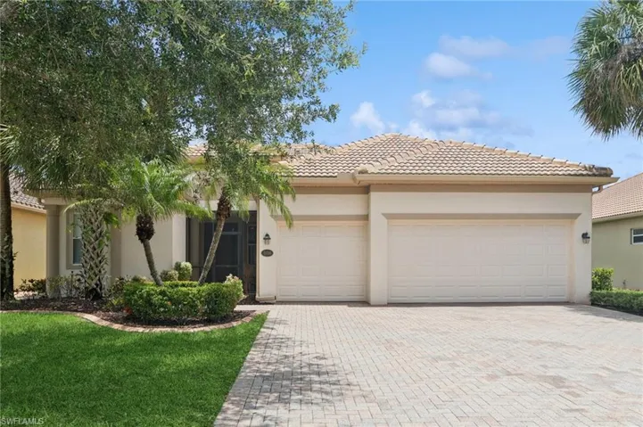 View of front facade featuring decorative driveway, an attached garage, stucco siding, a tiled roof, and a front yard