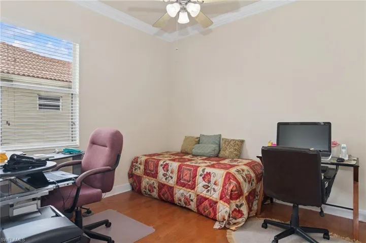 Bedroom with ornamental molding, a desk, wood finished floors, and ceiling fan