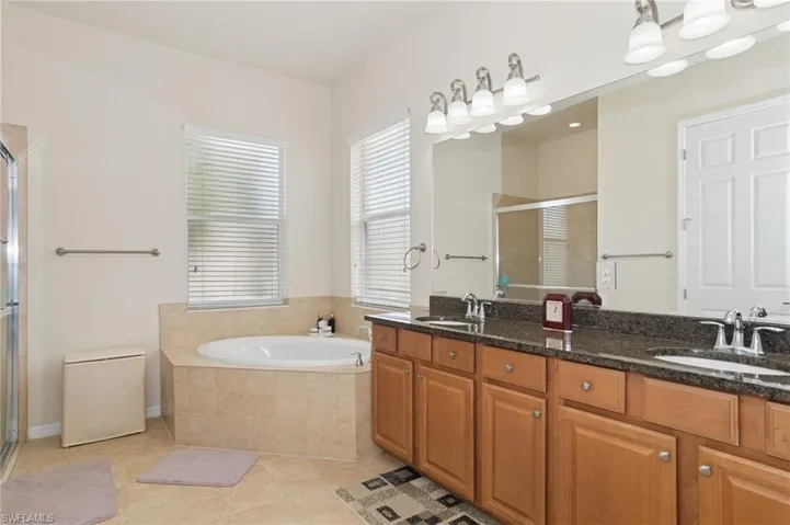 Full bath featuring a shower stall, double vanity, tile patterned flooring, and a garden tub