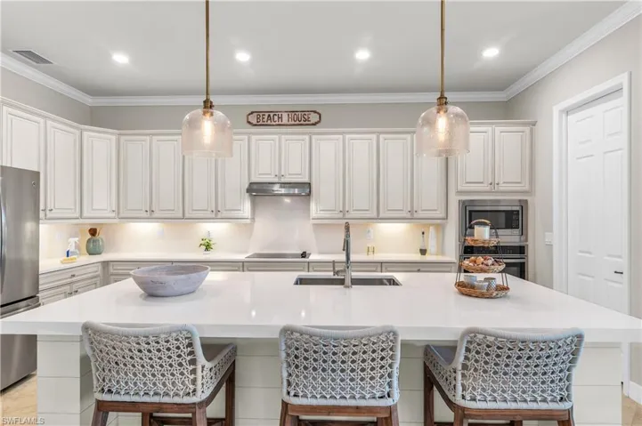 Clean and crisp white kitchen w/ center island, deep SS farmers sink, premium faucet/fixturest, large walk-in pantry... showcased with tons of canned and pendant lighting