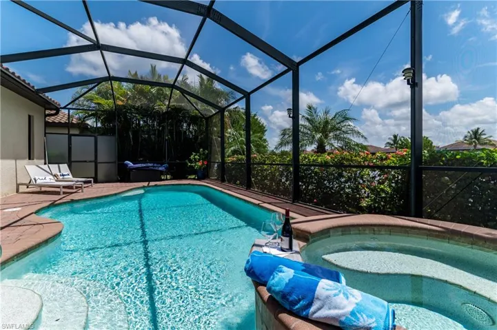 View of pool with a jacuzzi, a patio area, and a lanai