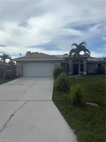 Ranch-style home featuring driveway, an attached garage, stucco siding, and a front lawn