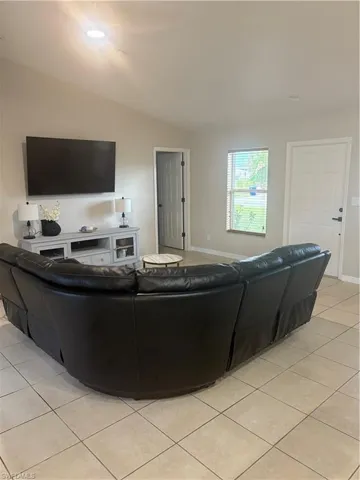 Living area with light tile patterned floors and vaulted ceiling