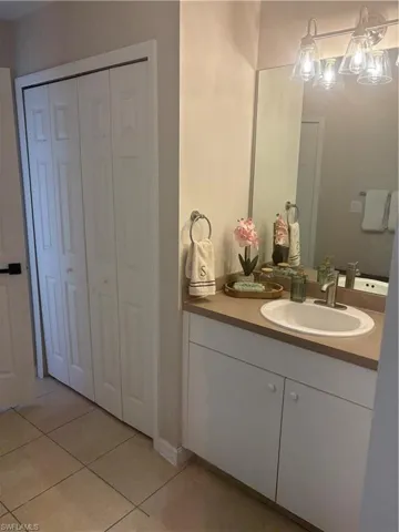 Bathroom with a closet, vanity, and tile patterned flooring